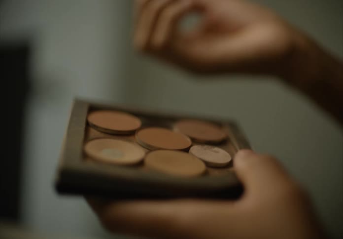 Woman uses a wide brush to apply makeup from a pallet