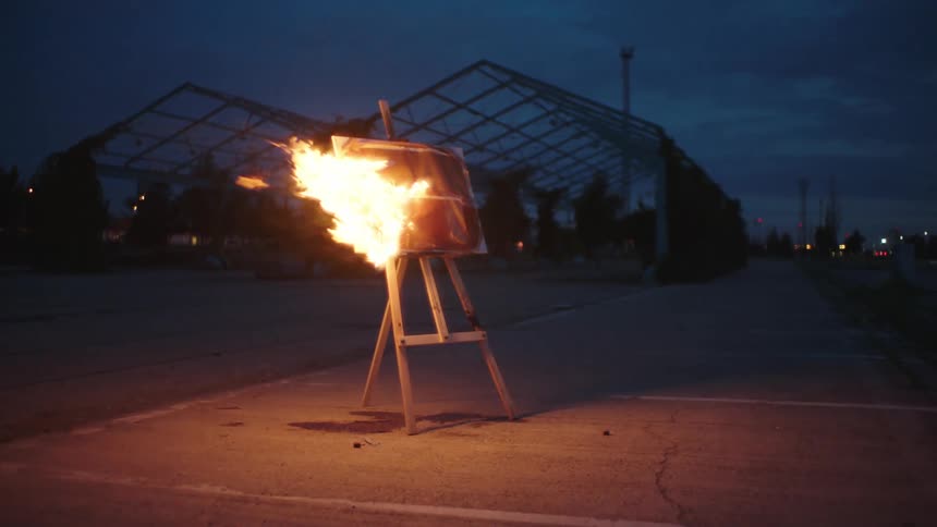 Art burning on an easel in an empty parking lot at dusk