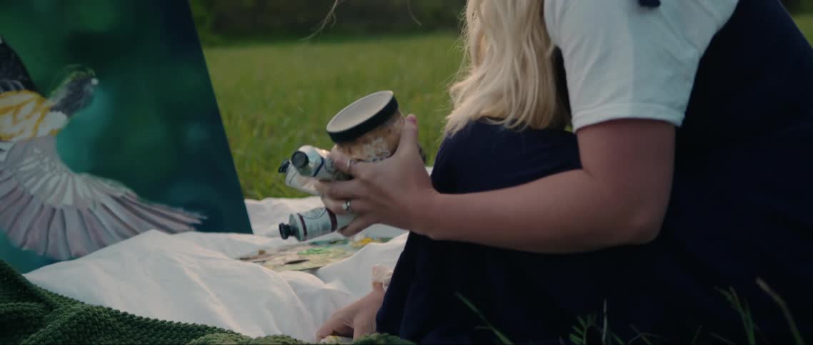 A woman places her paint by the canvas