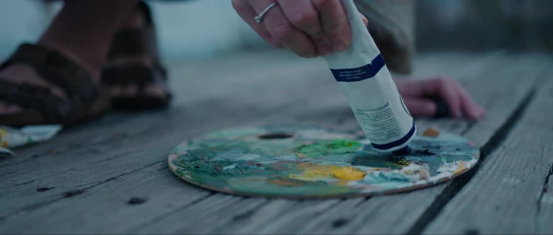 Hand squeezing paint from a tube into a color palette