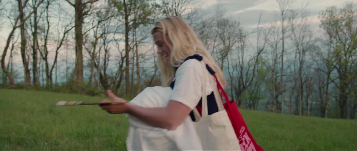 A woman is carrying bags on the field