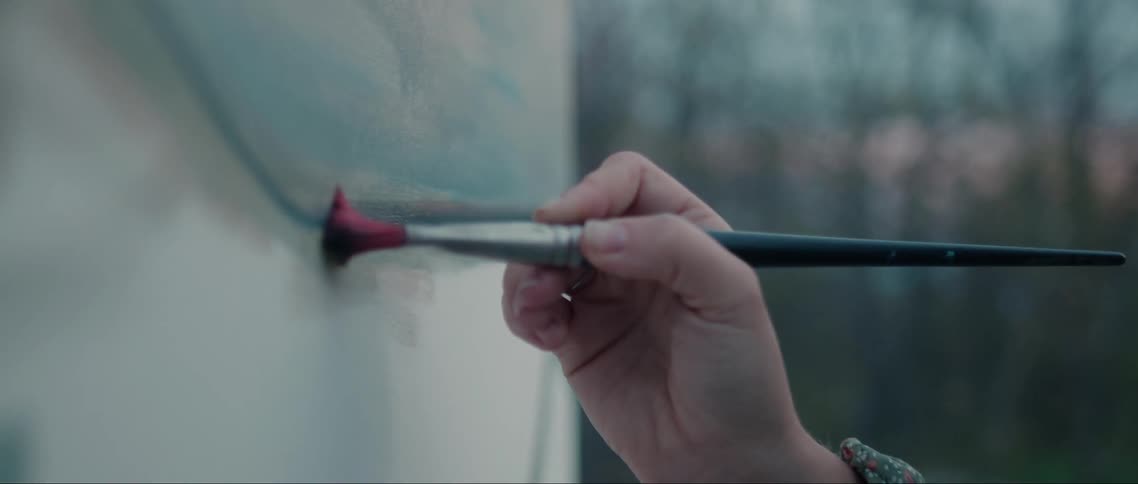 A hand holding a brush and painting a picture
