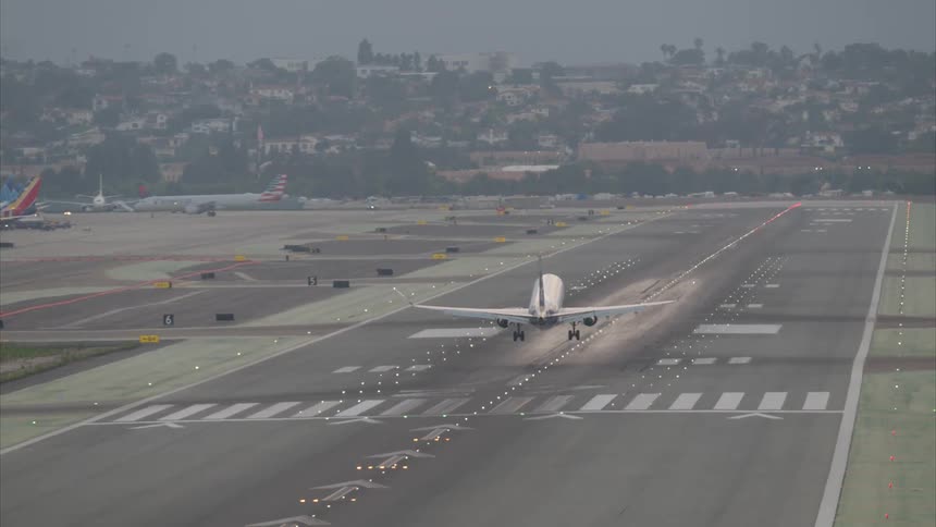 An airplane is landing on a runway in the city