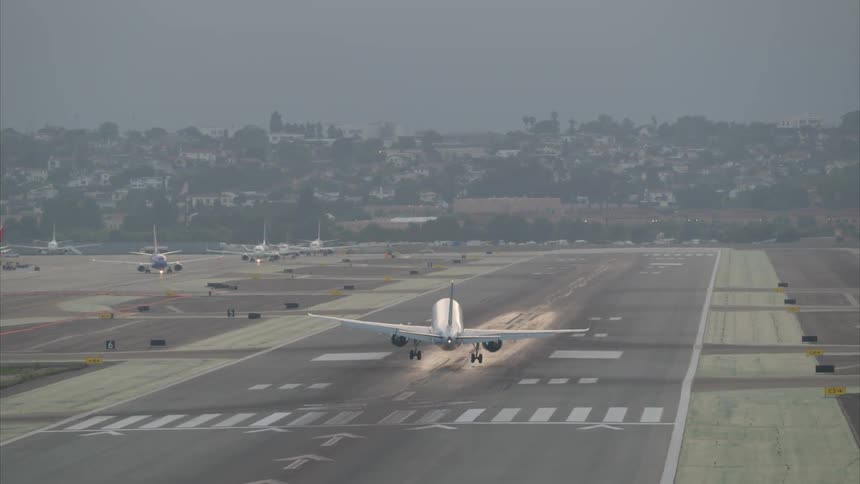 An airplane is landing on a runway in the city