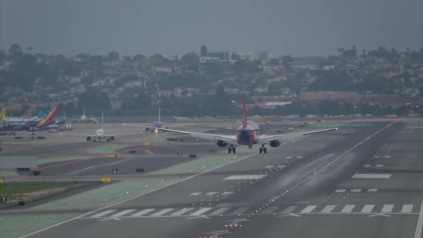 Airplane lands on an airport runway bordering a residential neighborhood on a foggy day