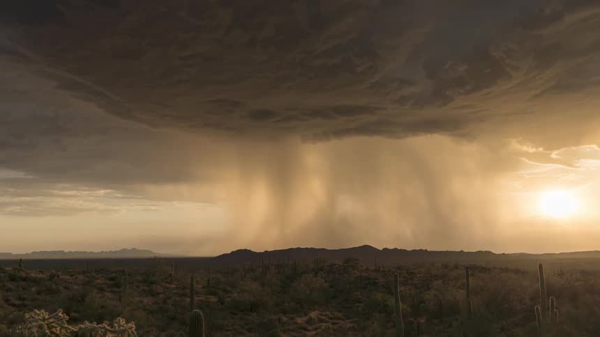 Timelapse footage captures distant rain falling from storm clouds over the desert landscape