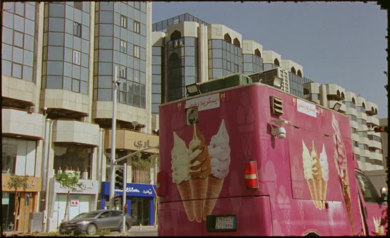 Ice cream food truck parked next to buildings with an emphasis on an air vent at the rear of the vehicle