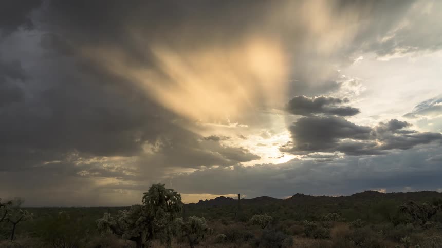 Time lapse of sunlight shining through storm clouds over the countryside