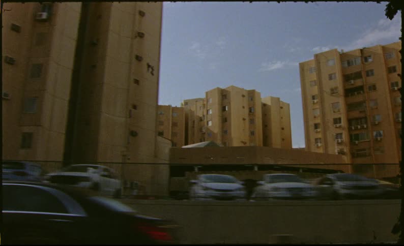 Traffic drives past an apartment building complex on a cloudy day