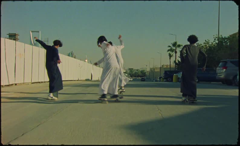 Four people are skateboarding down the road