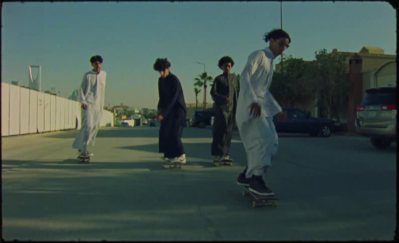 Four teenagers skateboarding on a paved street