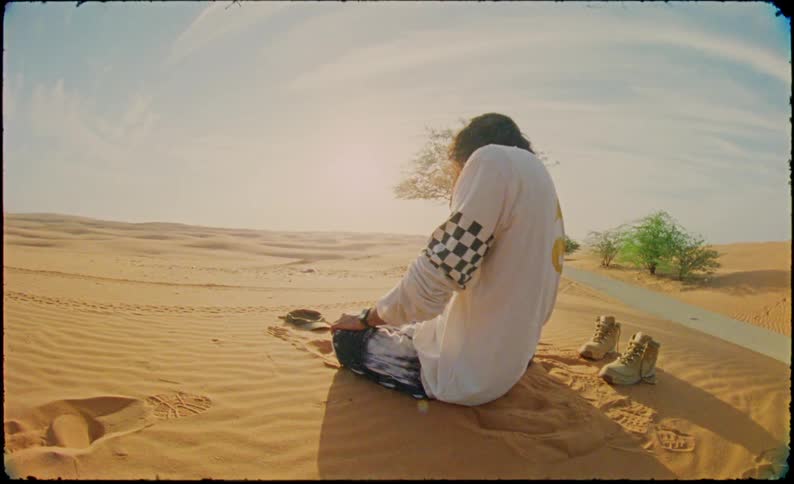 Person kneeling in prayer position by desert dunes