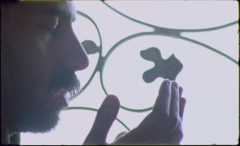 Side portrait of a man with his eyes closed with his hands open praying