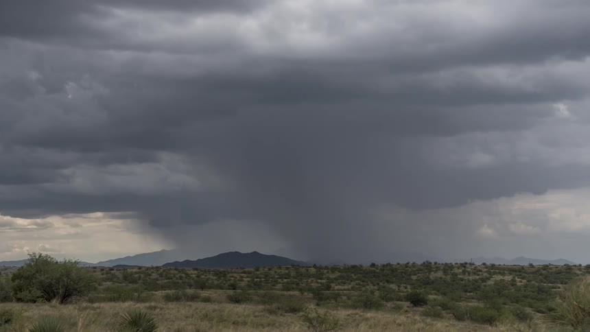 Panorama of a field with desert vegetation silhouette of mountains on the horizon in a sky with stormy clouds
