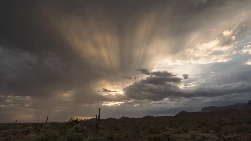 A desert region with a sky full of white and gray clouds blocking the sunlight