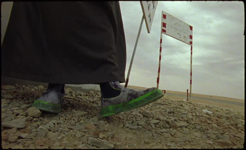 Feet of a person with boots on top of rocks in a desert environment