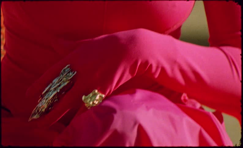 Closeup of a womans hands with her body covered in pink clothing putting on rings