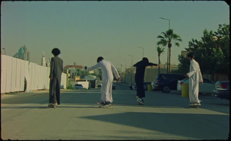 Four teenagers in black and white clothes riding skateboards