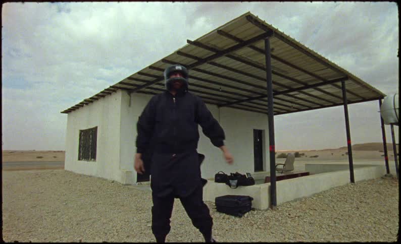 Man in a black suit and a protective helmet next to an isolated house