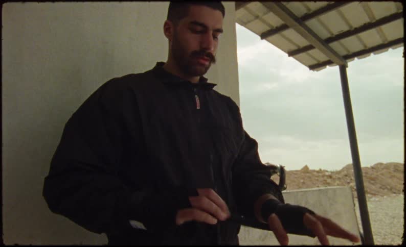 The man dressed in black is wrapping his hand with a black wrap