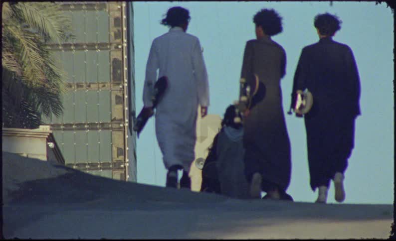 Teenagers walking up a street holding skateboards