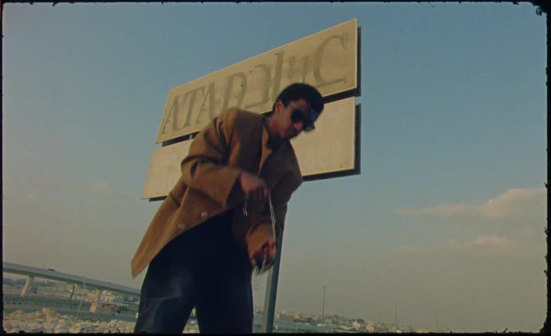 Young man taking a necklace from a suitcase and putting it around his neck