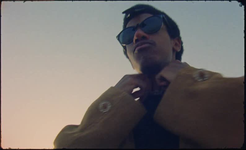 A man wearing sunglasses is wearing a beige coat