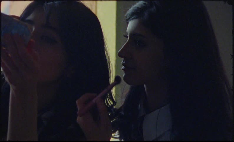 Two models indoors putting on makeup