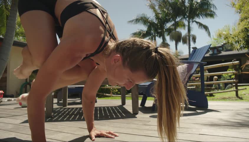 Woman in an acrobatic position with her arms on the ground and her legs suspended