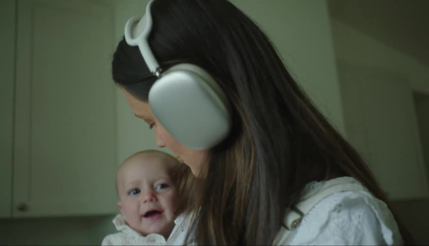 Mother with headphones holding her baby on her lap