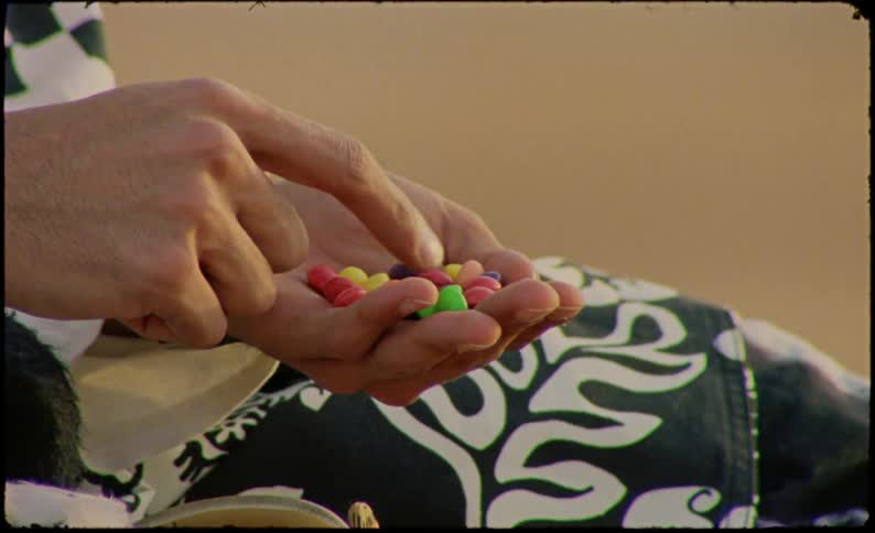 A man takes a few skittles from his hand and eats them