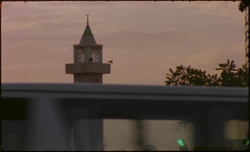 The minaret of a mosque against a cloudy sky at dusk caught on vintage film