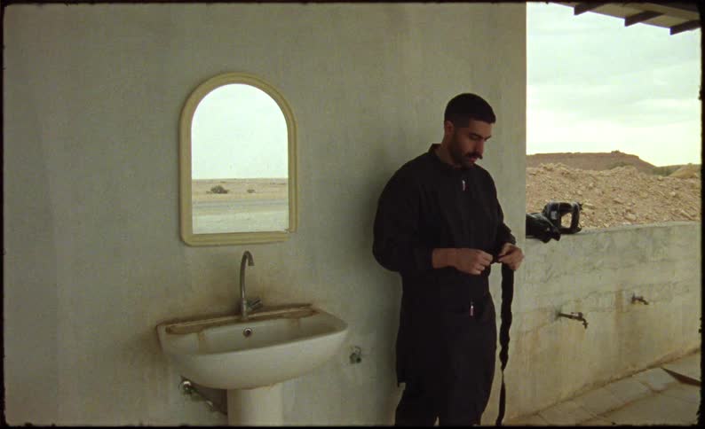 Man next to a sink and a mirror taking off the bandage and rebandaging his wrist
