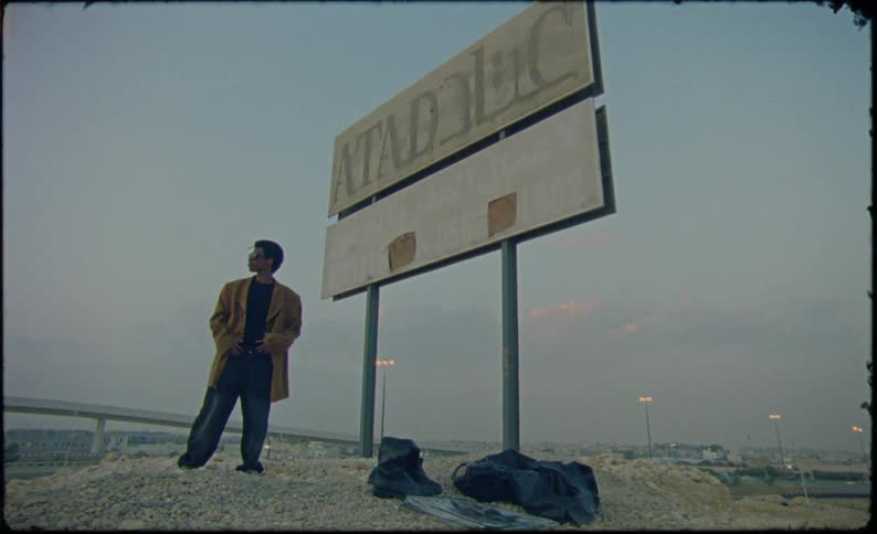 Man in a brown coat and sunglasses enjoying the vibe in an outdoor setting