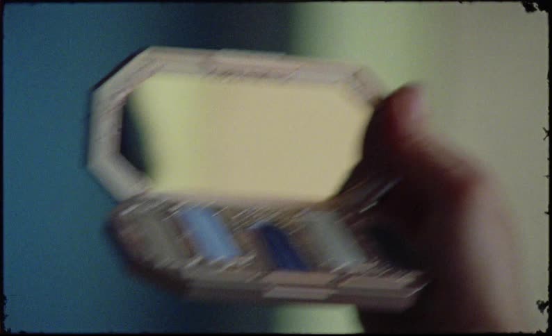 Woman putting on makeup looking at a small mirror that she holds in her hands