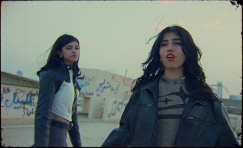 The two females are moving around the roof top hugging each other and looking at the camera