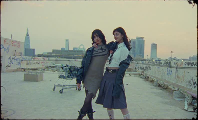 Two young models in fashionable clothes in an openair building