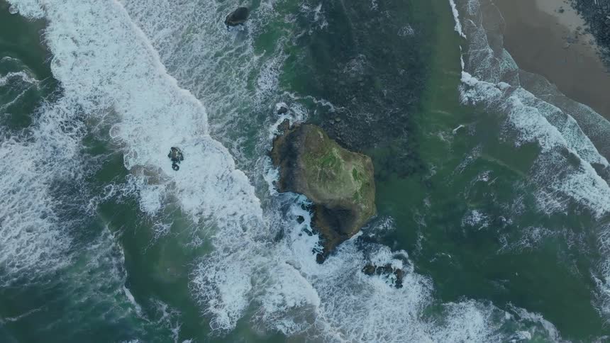 Aerial view of a coastline from above where waves crash against rugged rocks