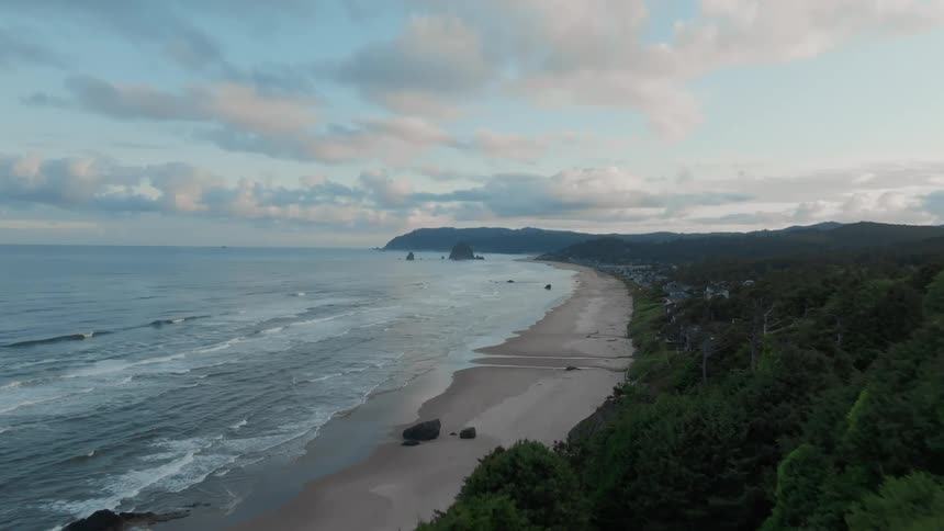 Aerial panorama of a highway alongside a beach on a partly cloudy day