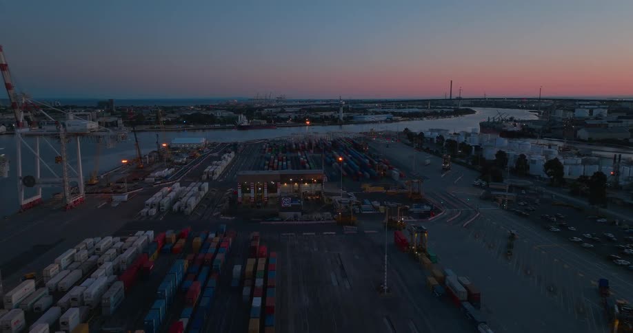 A port with several containers and machines moving them and it is dusk