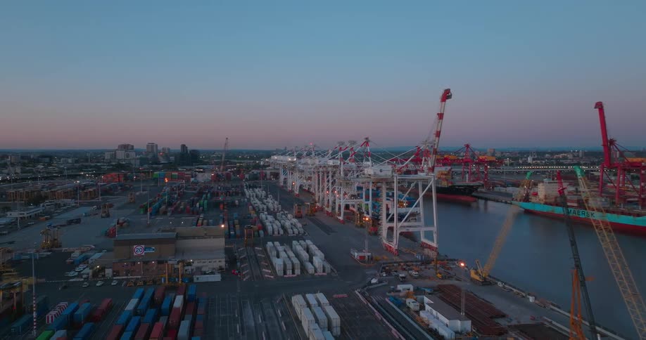 A port facility with ships sits next to a river outside a city