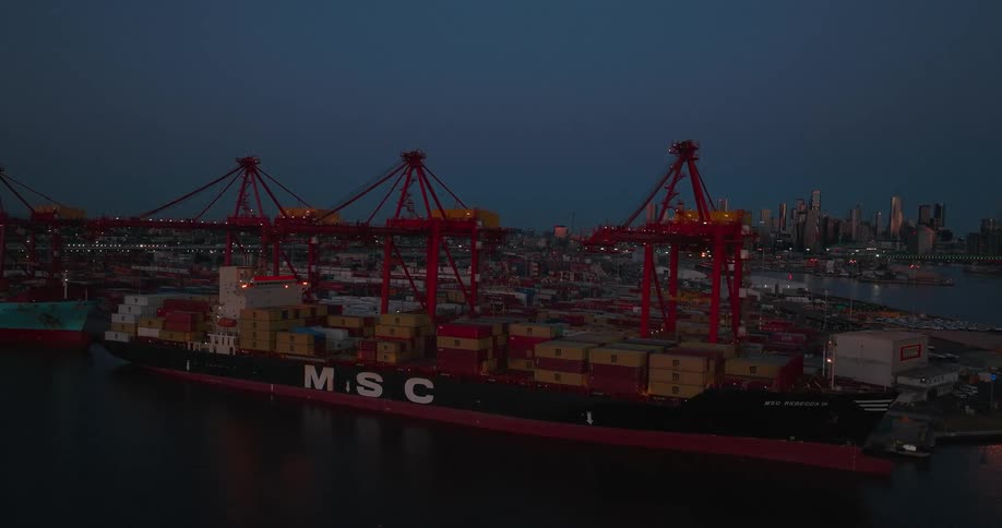 Cargo boat full of containers parked in a port at night
