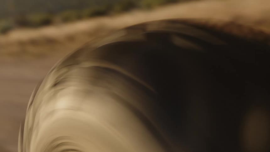 A large tire rolls on the dirt road