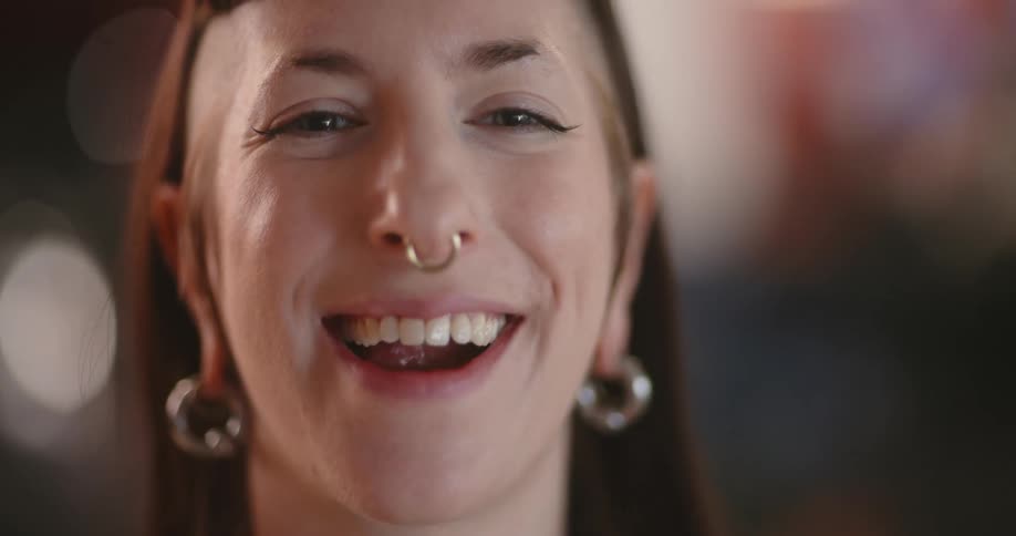 The face of a young woman who is smiling and she has a nose ring