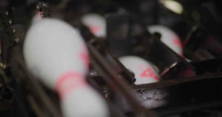A machine racks up bowling pins to get them ready to play