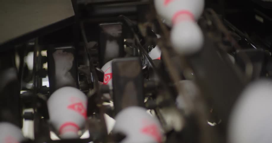 A machine racks up bowling pins to get them ready to play
