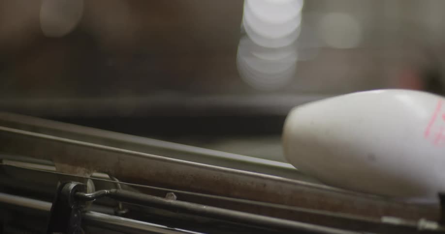 Some white bowling pins being taken to the left by a machine