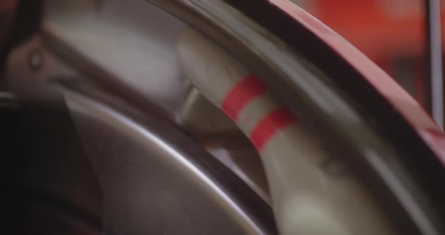 A metal machine that has white bowling pins attached to it to move them