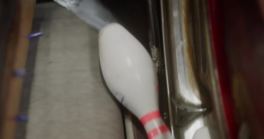 The bowling pins are knocked down by a bowling ball and they fall and are pushed into the machine that lines them back up