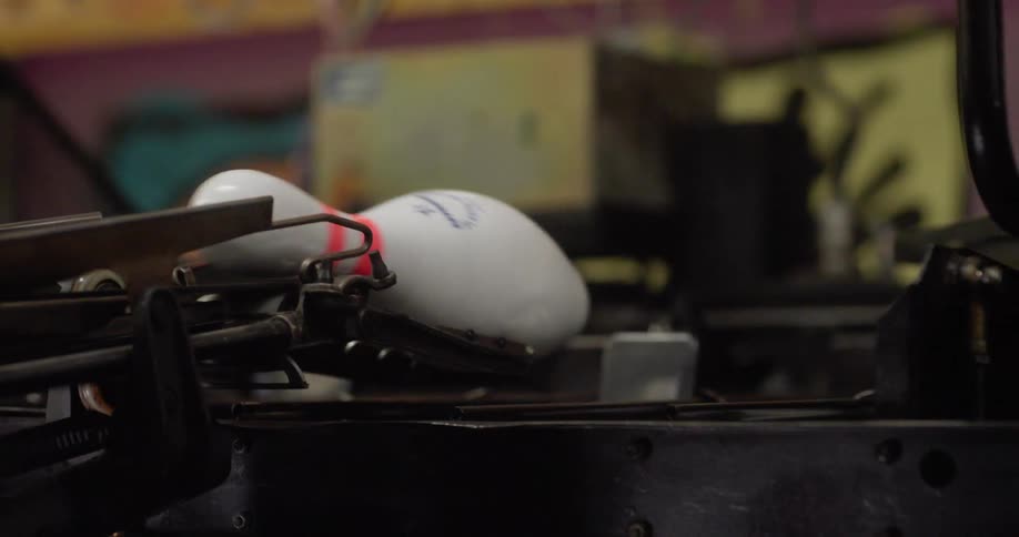 A machine arranges bowling pins to put them in place